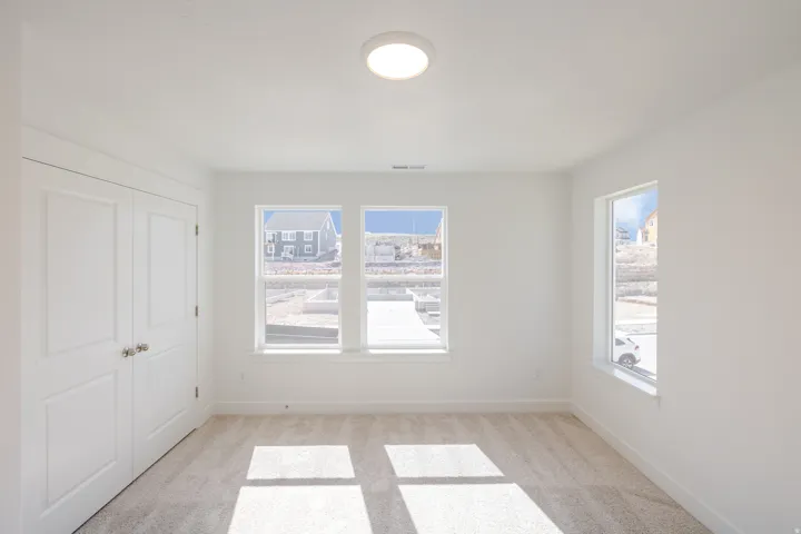 Bright room featuring white walls, a flush-mount ceiling light, and light-toned carpeting