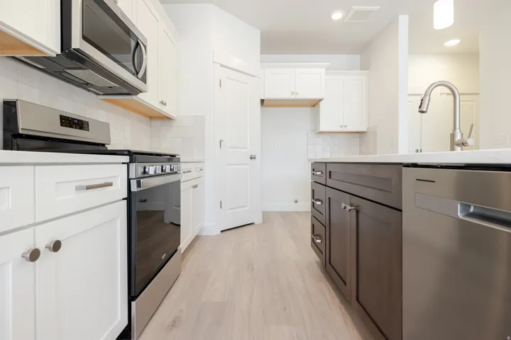 Modern kitchen featuring light wood-finish flooring and a white subway tile backsplash