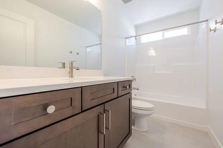 Bathroom featuring a wood-finish vanity with a light-colored countertop, an integrated sink, a brushed nickel faucet, and a large mirror