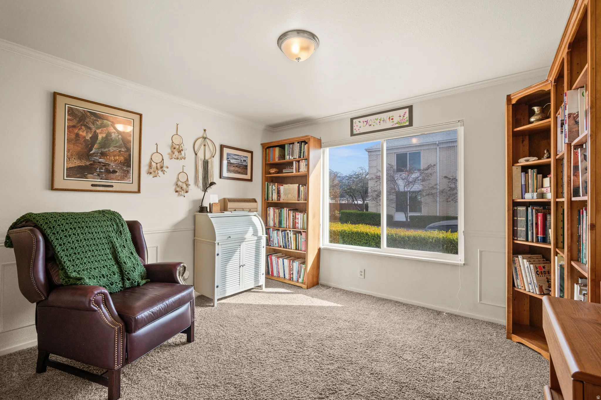 Living area with crown molding and light colored carpet
