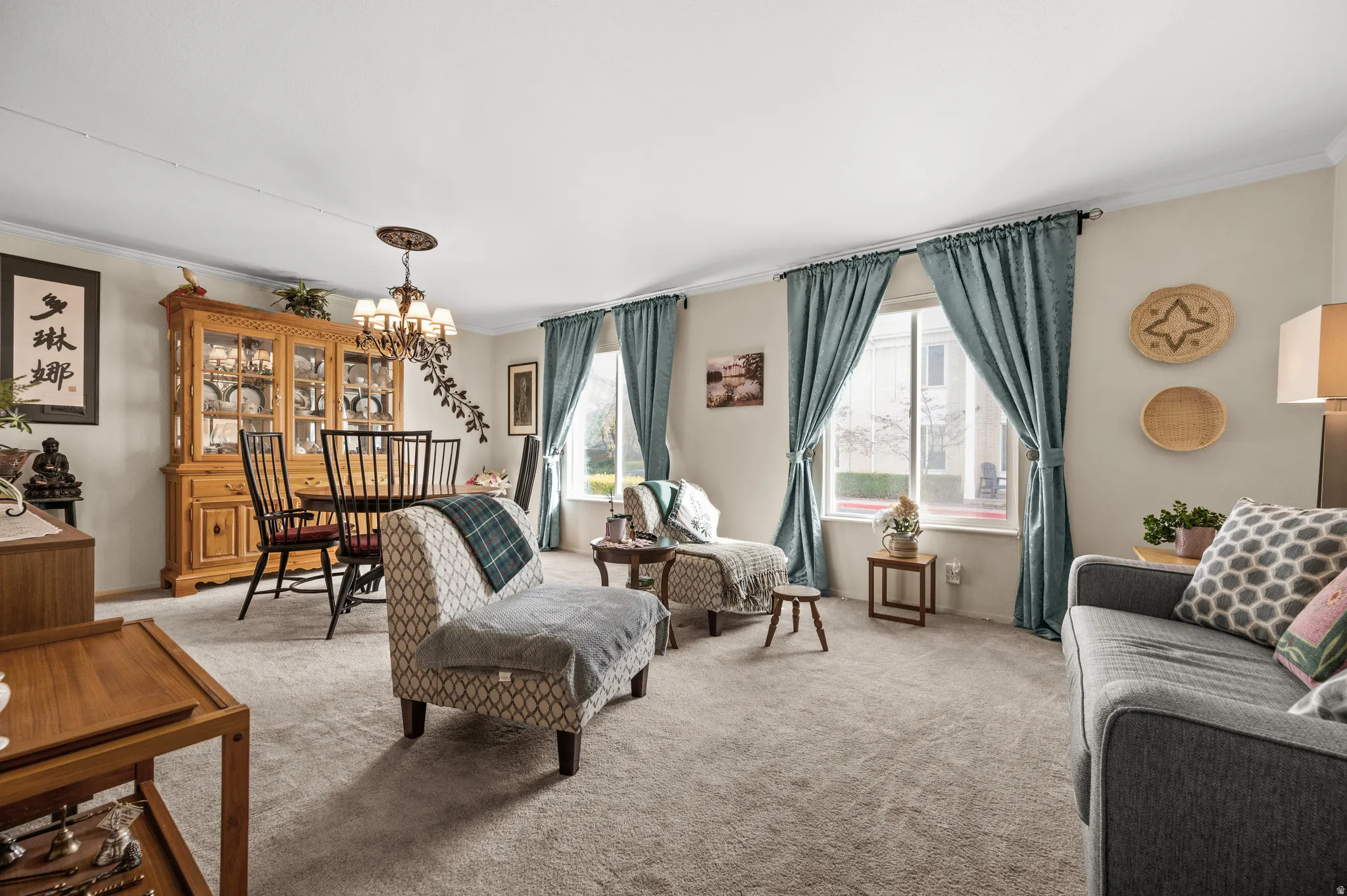 Living room featuring crown molding, hanging lights, and light carpet