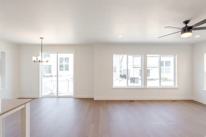 Spacious interior featuring wood-finish flooring, white walls, multiple windows, recessed lighting, and a ceiling fan