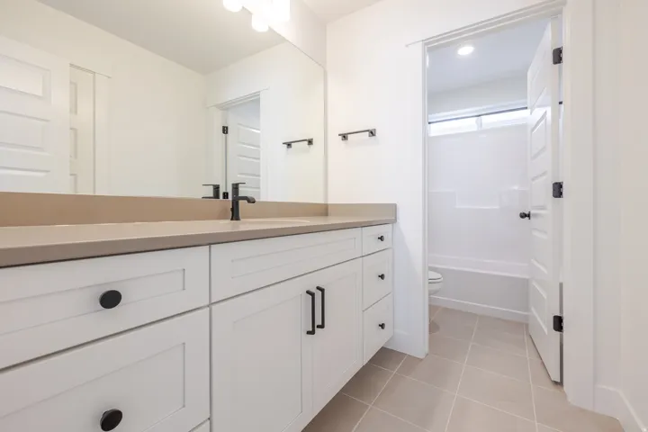 Bathroom featuring a white shaker-style vanity with a light-toned countertop, a rectangular undermount sink, and a matte black faucet