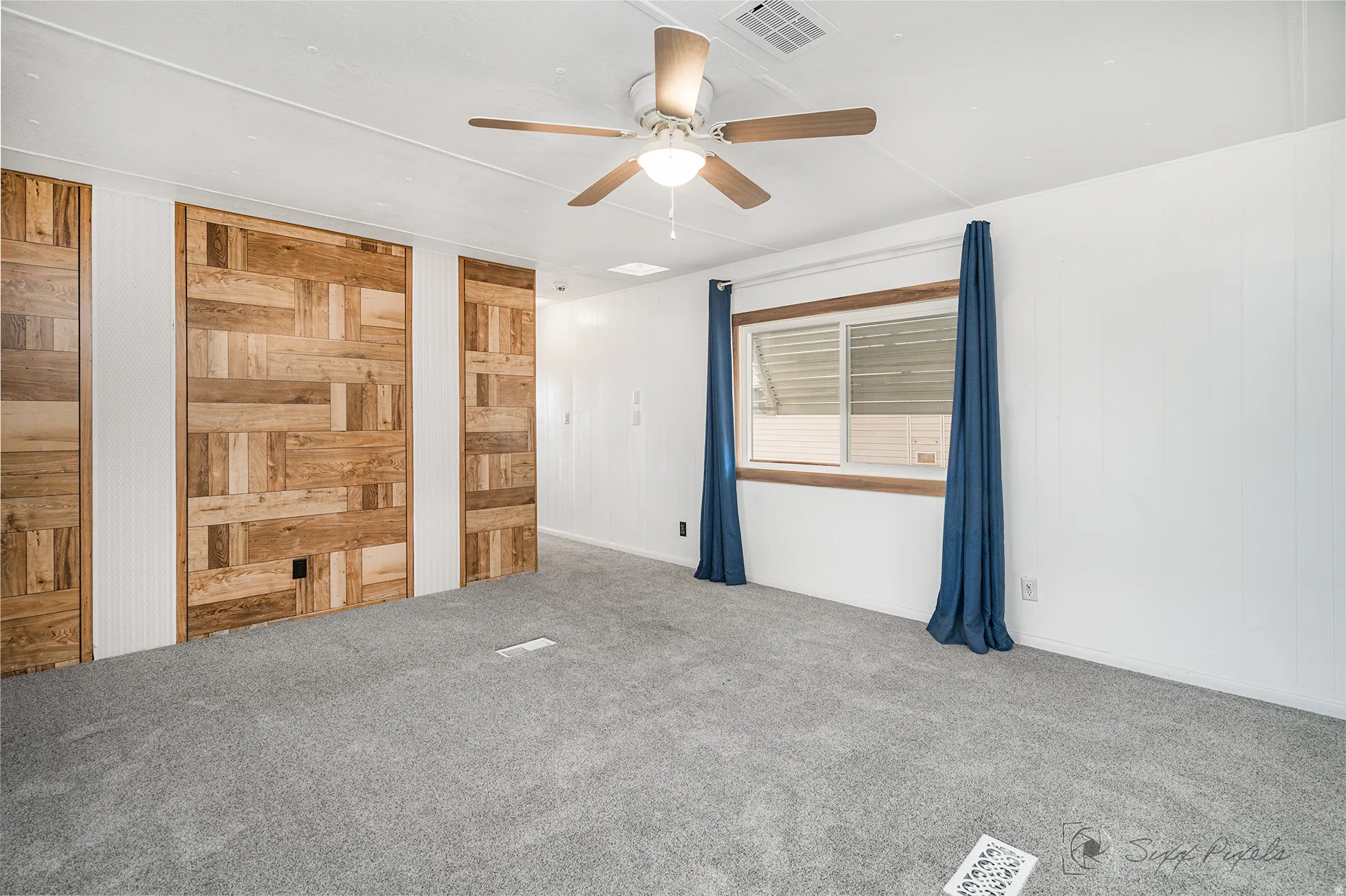Unfurnished bedroom with a ceiling fan, wood walls, and carpet