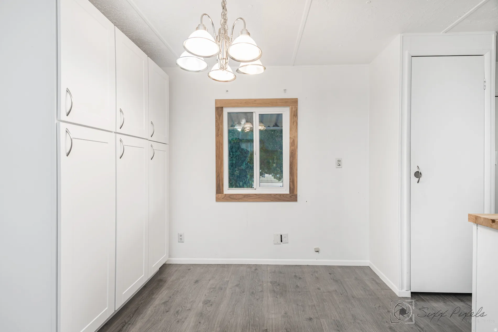 Unfurnished dining area featuring a chandelier and dark wood-type flooring