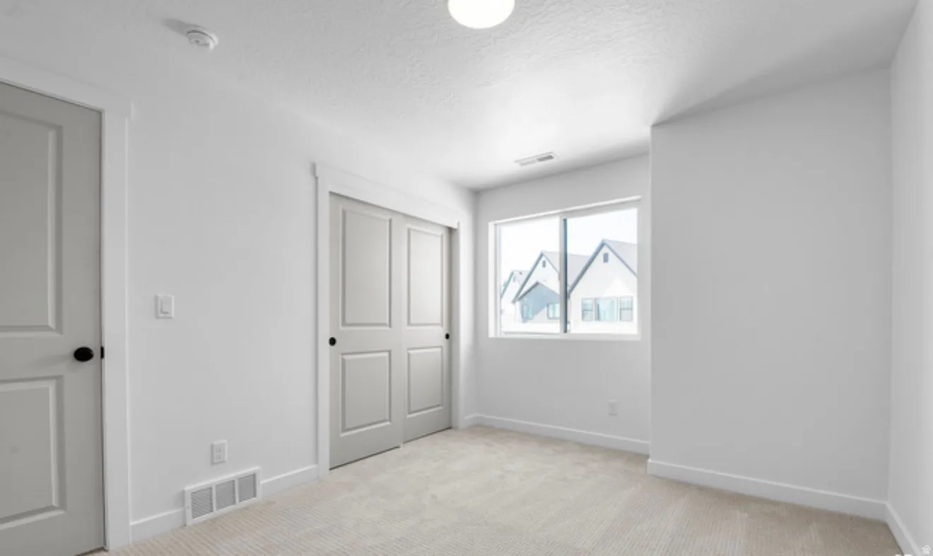 Unfurnished bedroom with light carpet, a closet, and a textured ceiling
