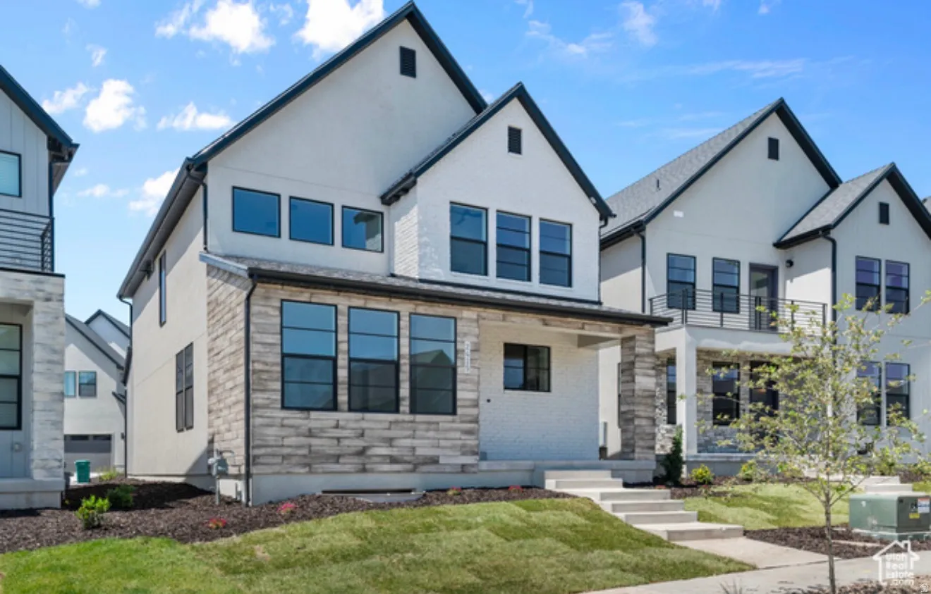 View of front of property featuring a front yard, stucco siding, and a balcony