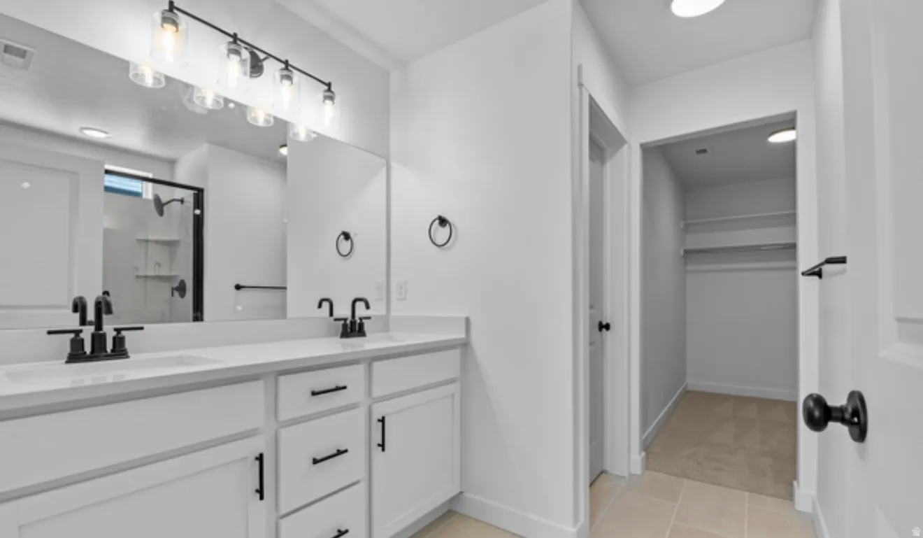 Bathroom featuring double vanity, a stall shower, a walk in closet, light colored carpet, and light tile patterned floors