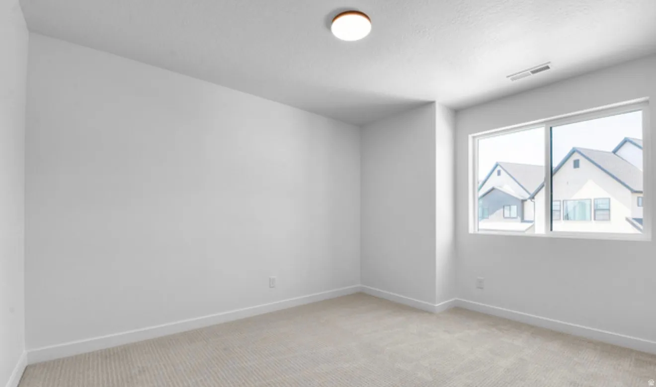 Spare room with light colored carpet and a textured ceiling