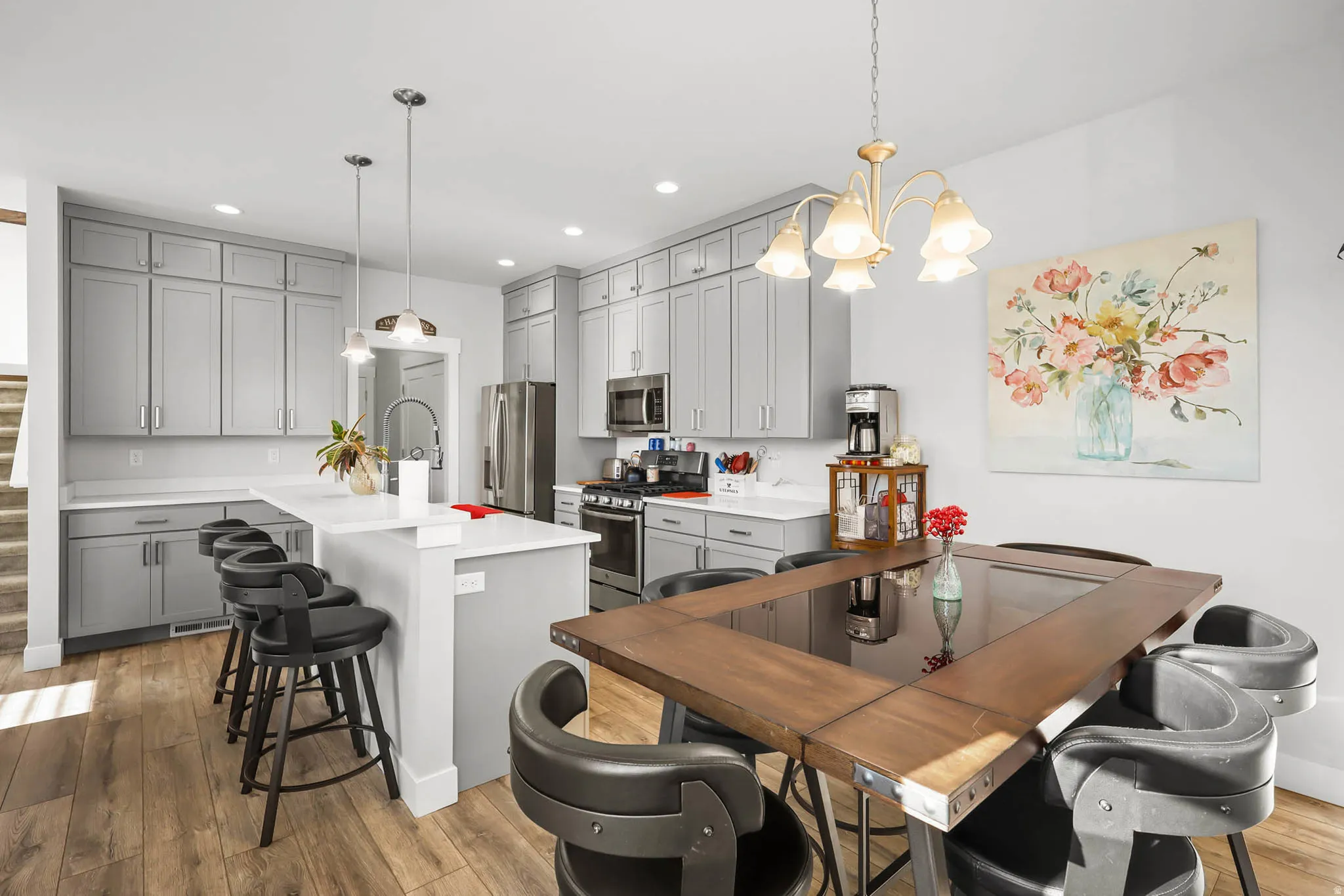 Kitchen featuring gray cabinets, a kitchen breakfast bar, stainless steel appliances, and light wood-style floors