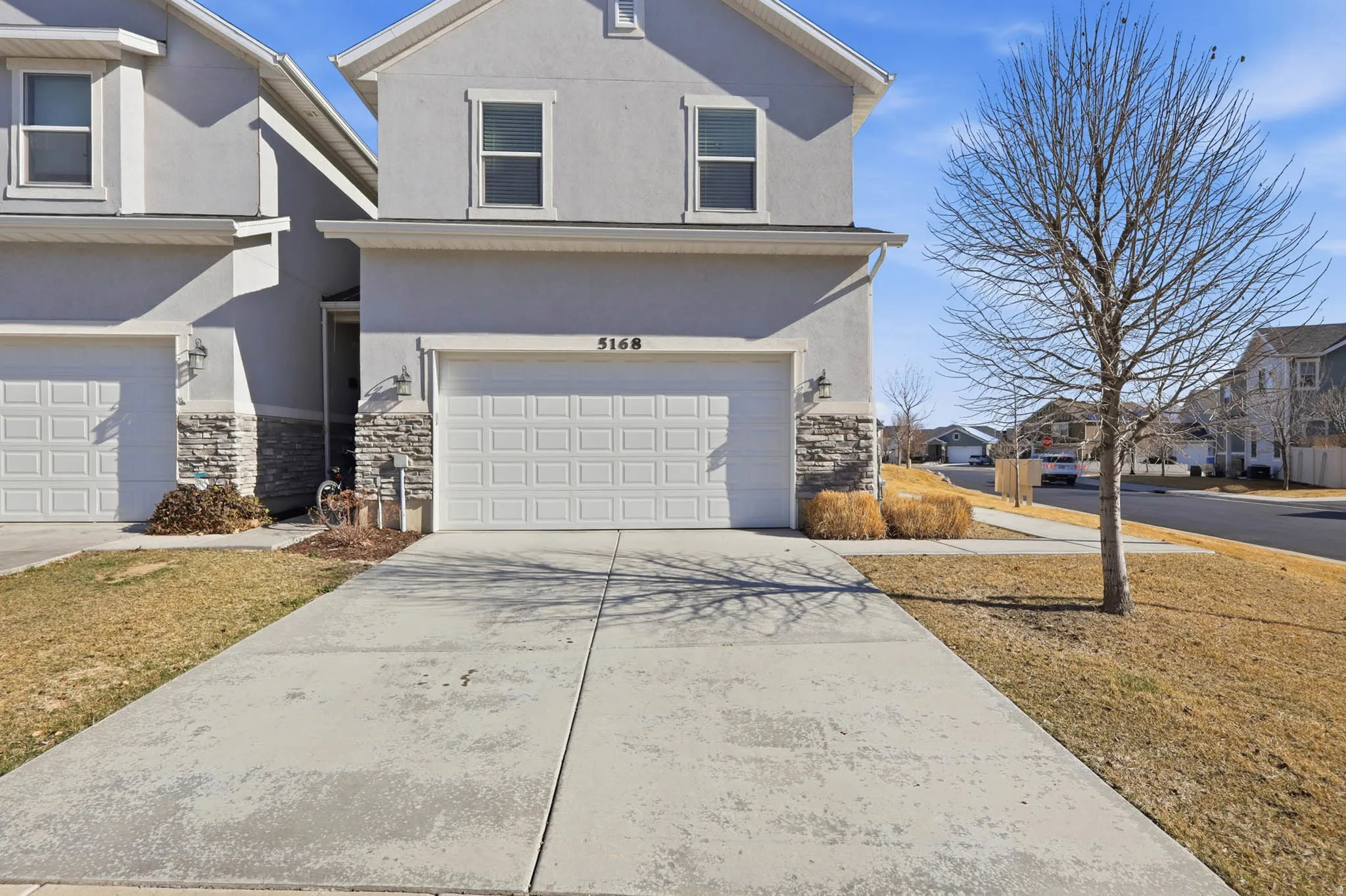 View of front of home with stone siding, stucco siding, an attached garage, and concrete driveway