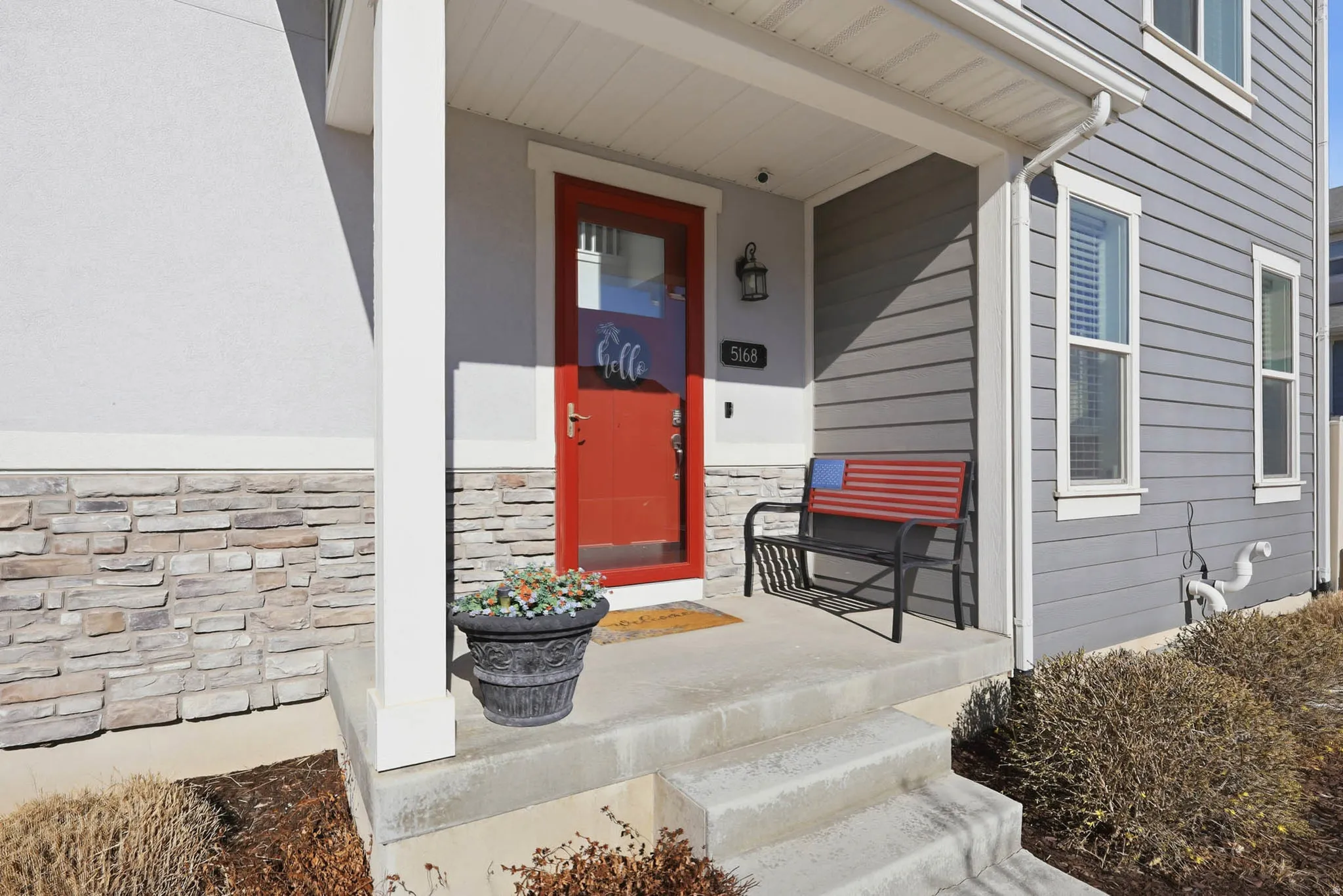 Property entrance with covered porch and stone siding