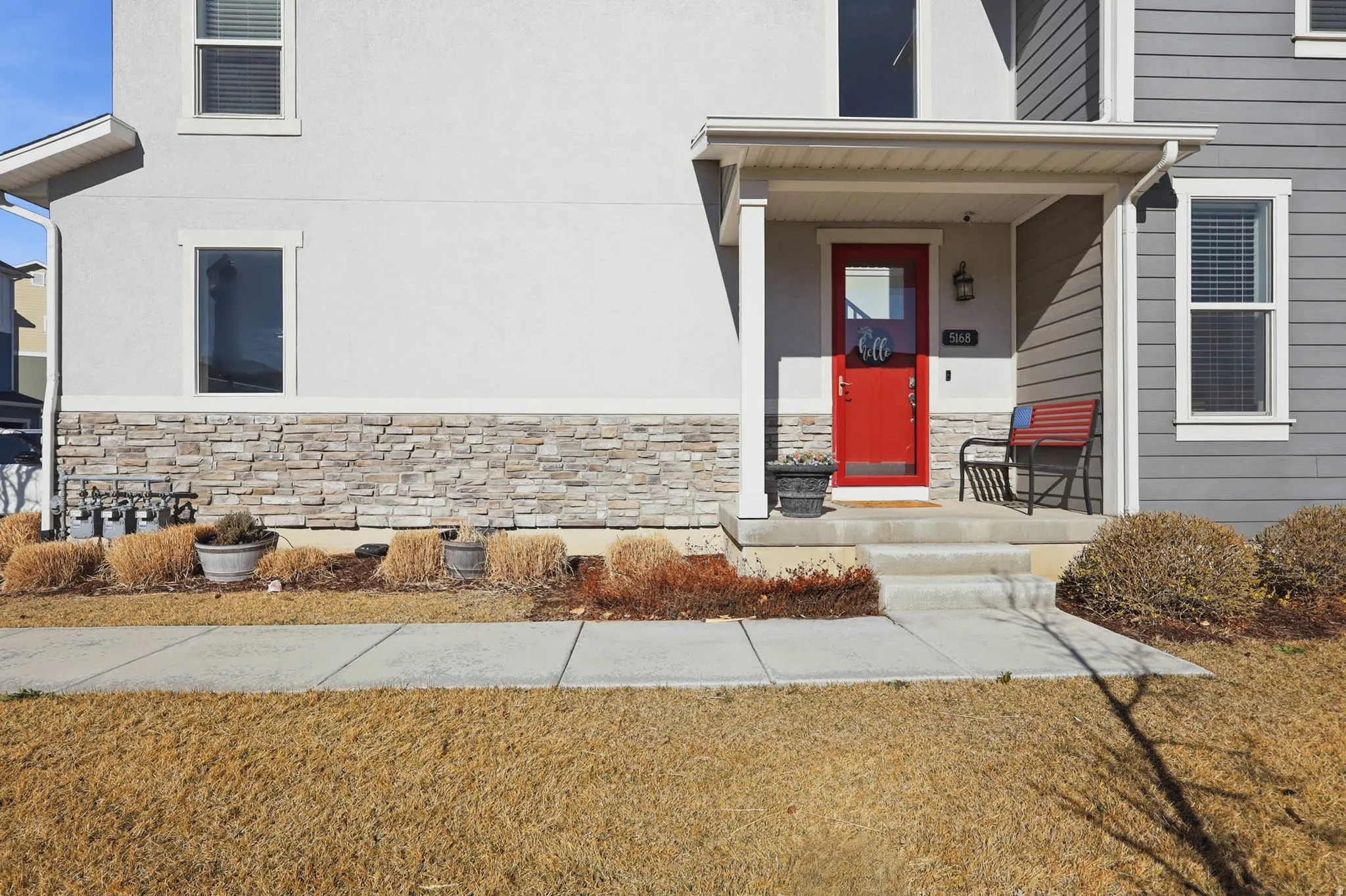 View of exterior entry with stone siding, covered porch, and stucco siding