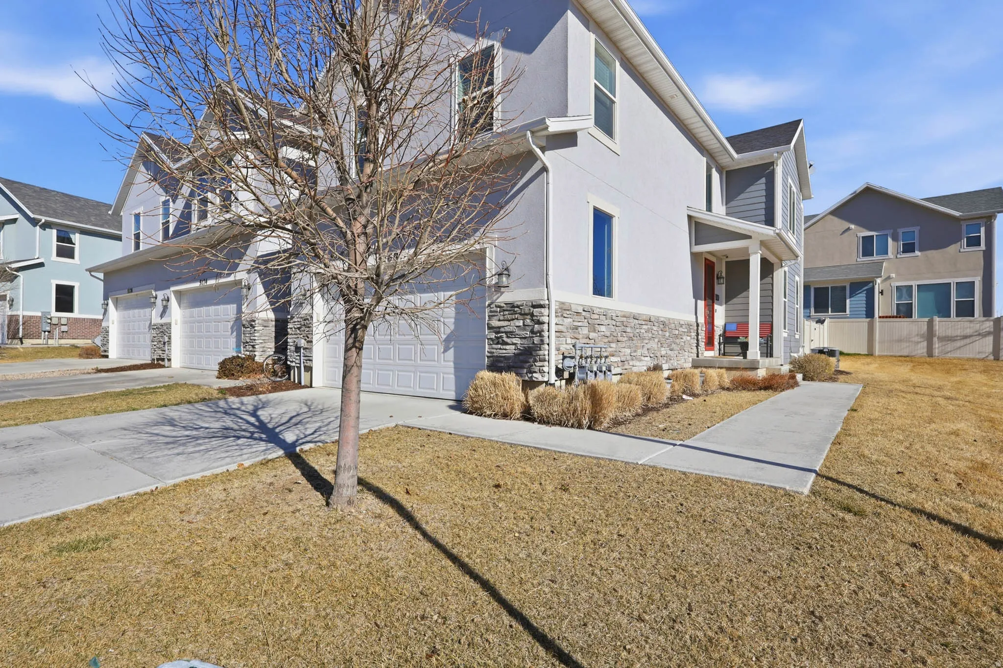Traditional-style house with an attached garage, stone siding, concrete driveway, stucco siding, and a porch