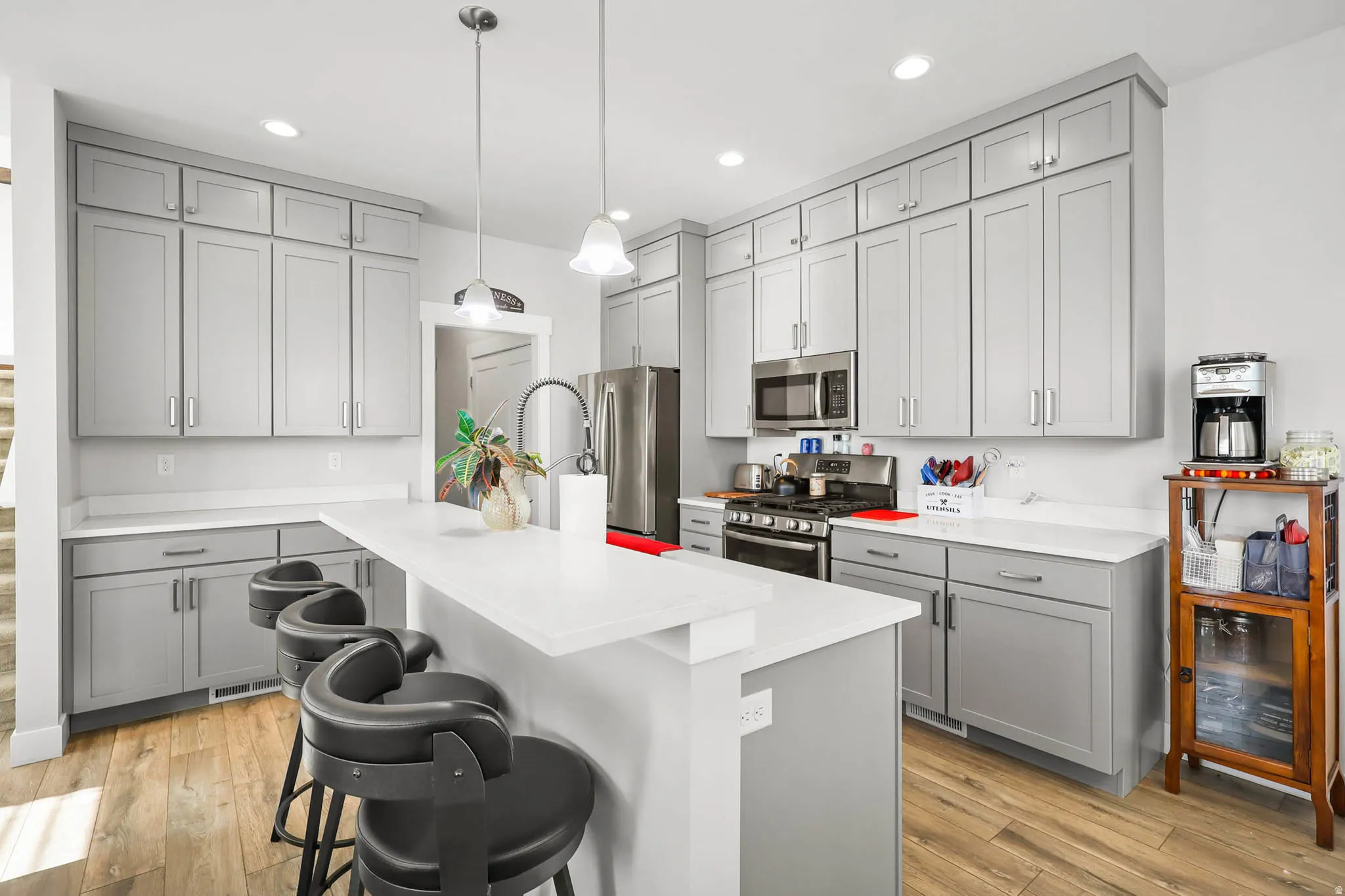 Kitchen with gray cabinets, stainless steel appliances, a kitchen island, and light wood-style floors