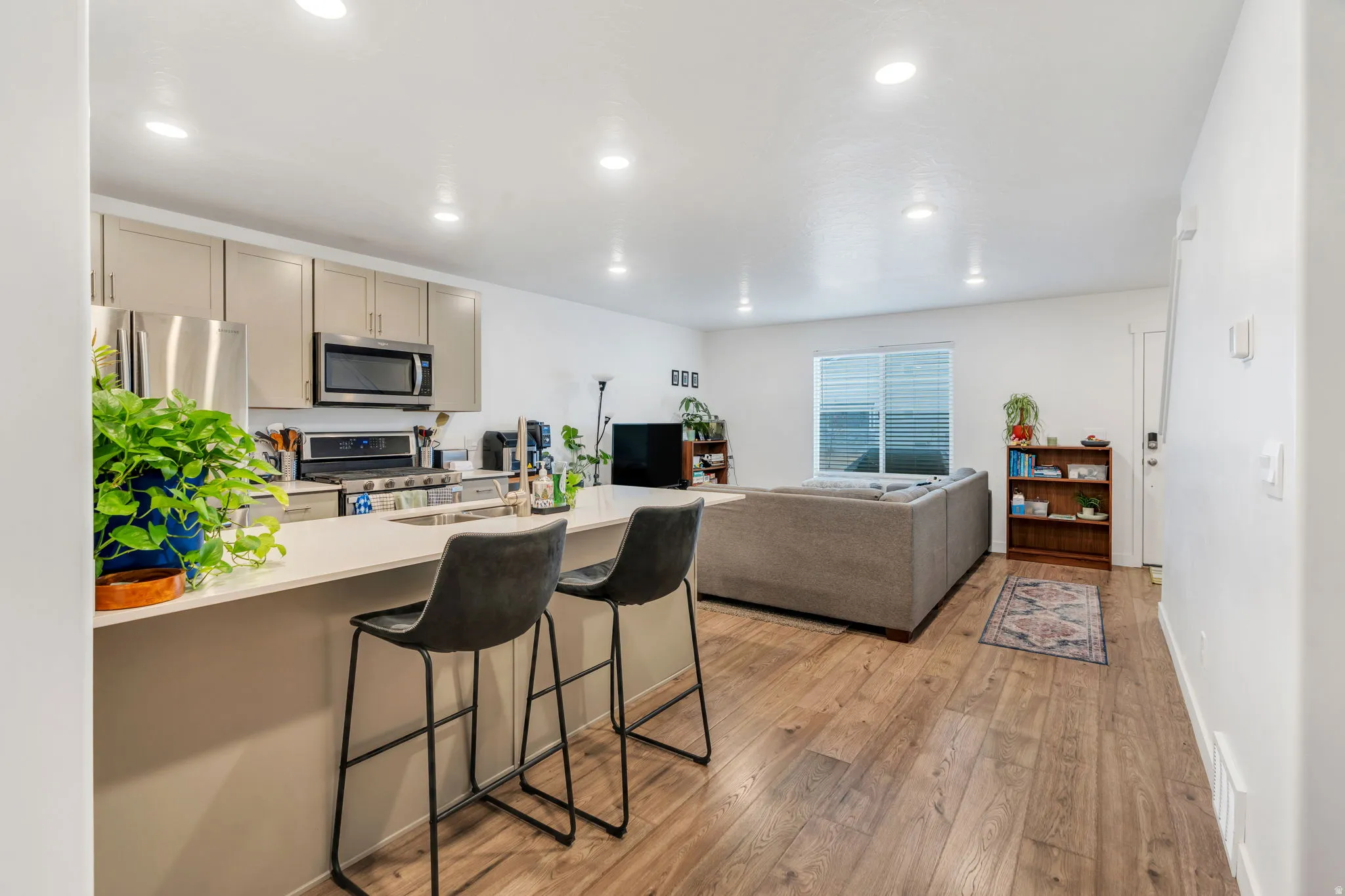 Kitchen featuring a breakfast bar, open floor plan, stainless steel appliances, light wood finished floors, and a peninsula