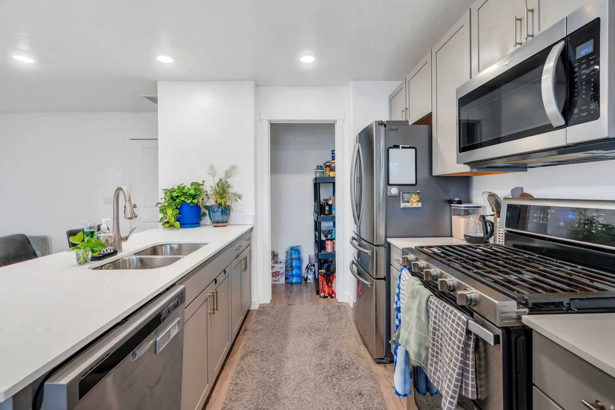 Kitchen featuring stainless steel appliances, gray cabinets, light stone countertops, light wood finished floors, and recessed lighting