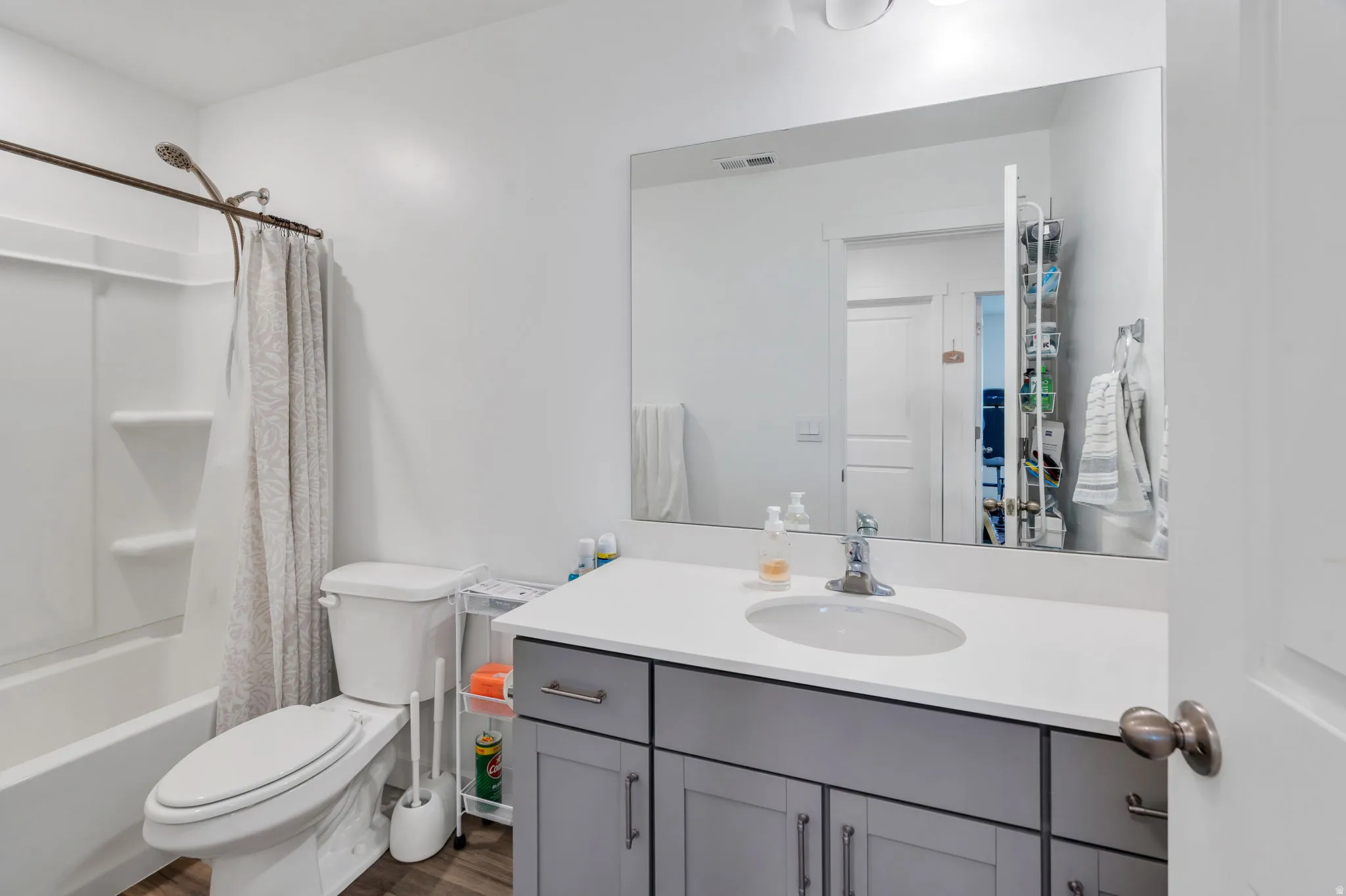 Bathroom with vanity, shower / tub combo with curtain, and dark wood-style flooring