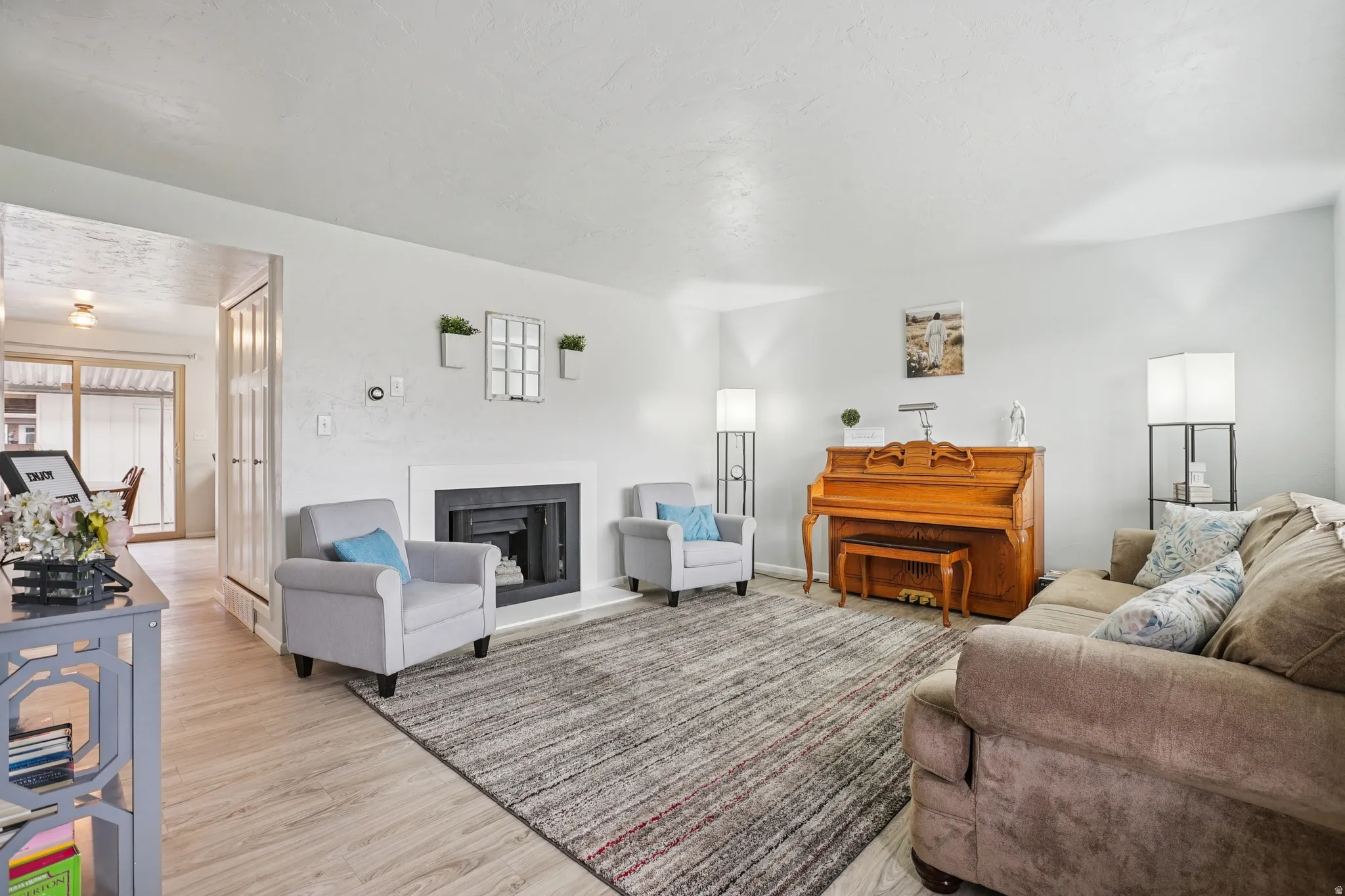 Living area featuring light wood-style flooring and a fireplace with raised hearth