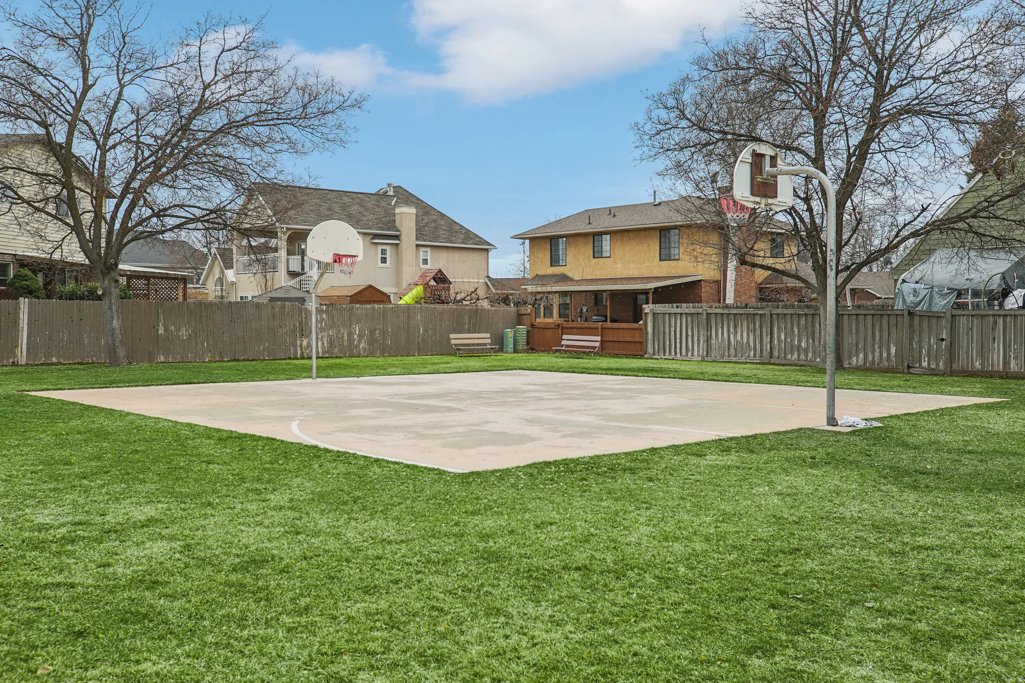View of sport court featuring basketball hoop and a residential view