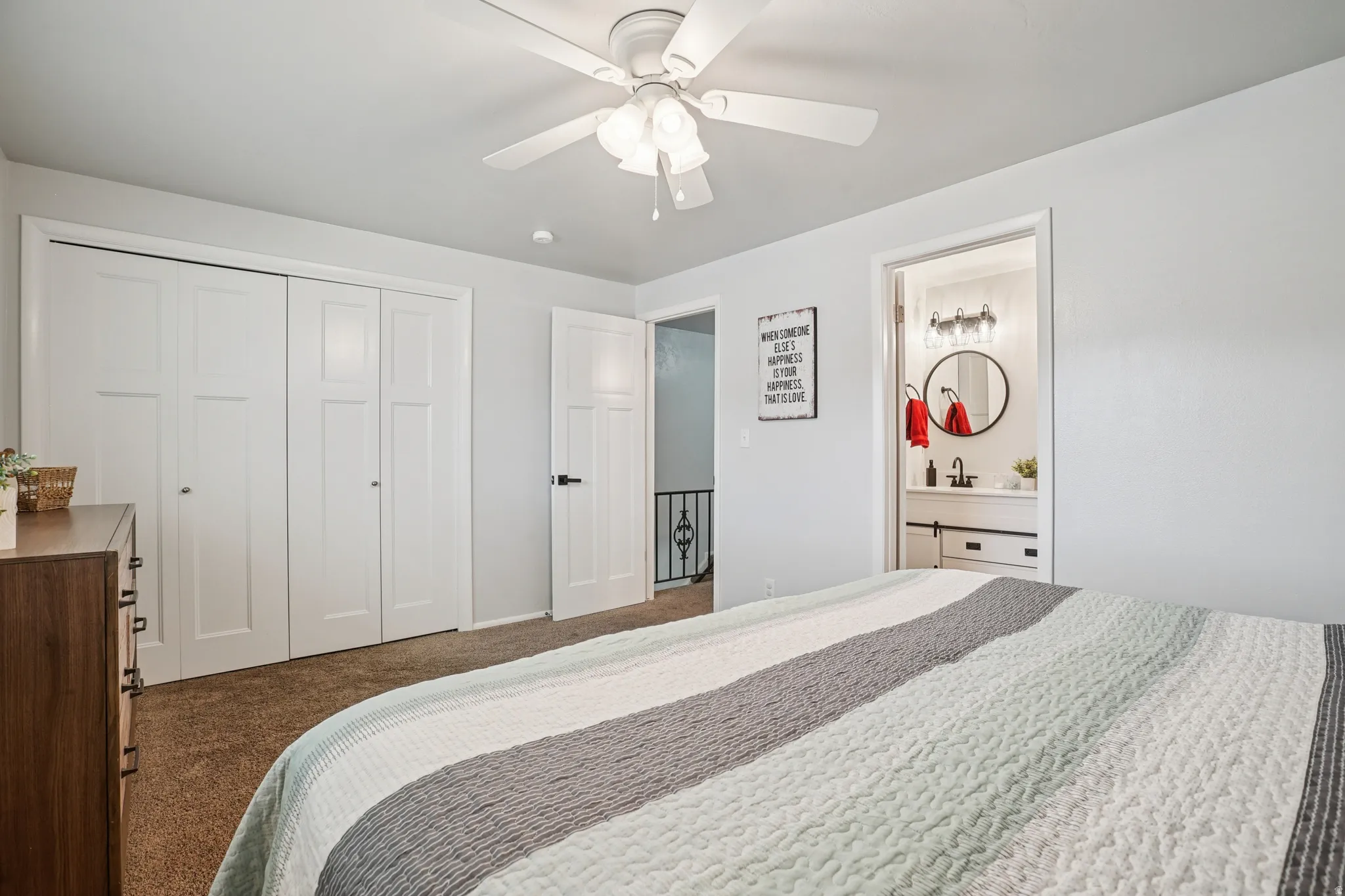Bedroom featuring a closet, dark colored carpet, a ceiling fan, and ensuite bath