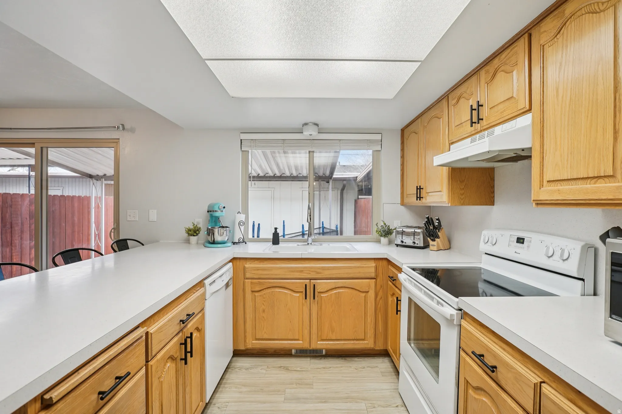 Kitchen with white appliances, light countertops, light wood-style floors, and wood finish cabinetry