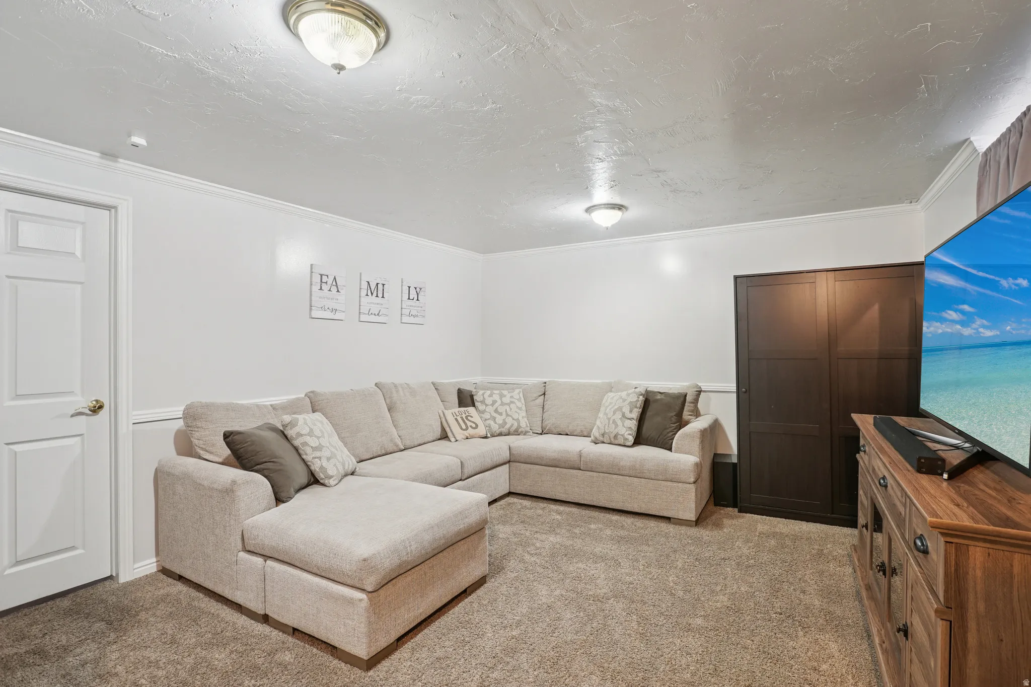 Living area featuring light colored carpet, ornamental molding, and a textured ceiling