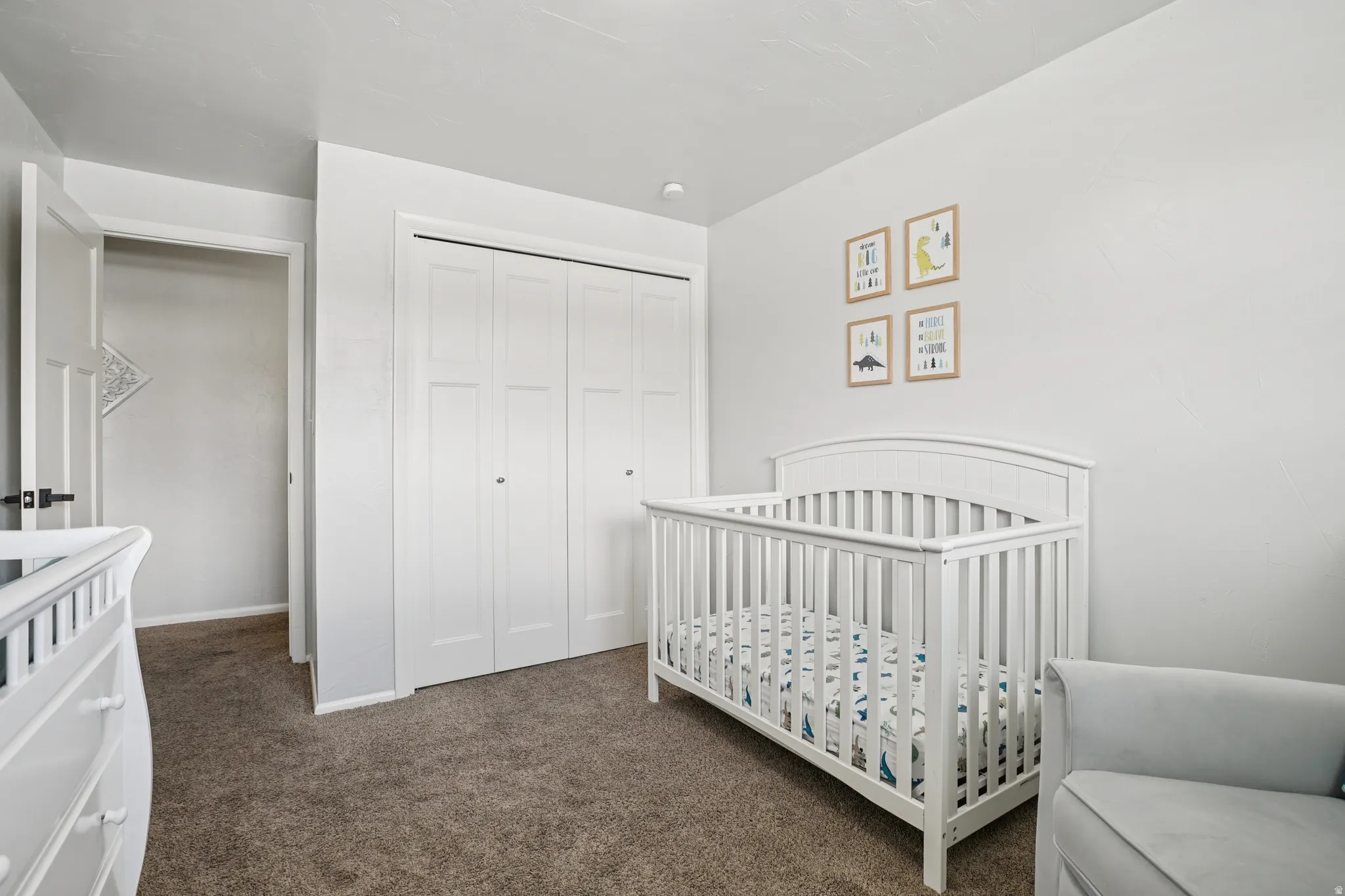 Bedroom with a nursery area, dark colored carpet, and a closet
