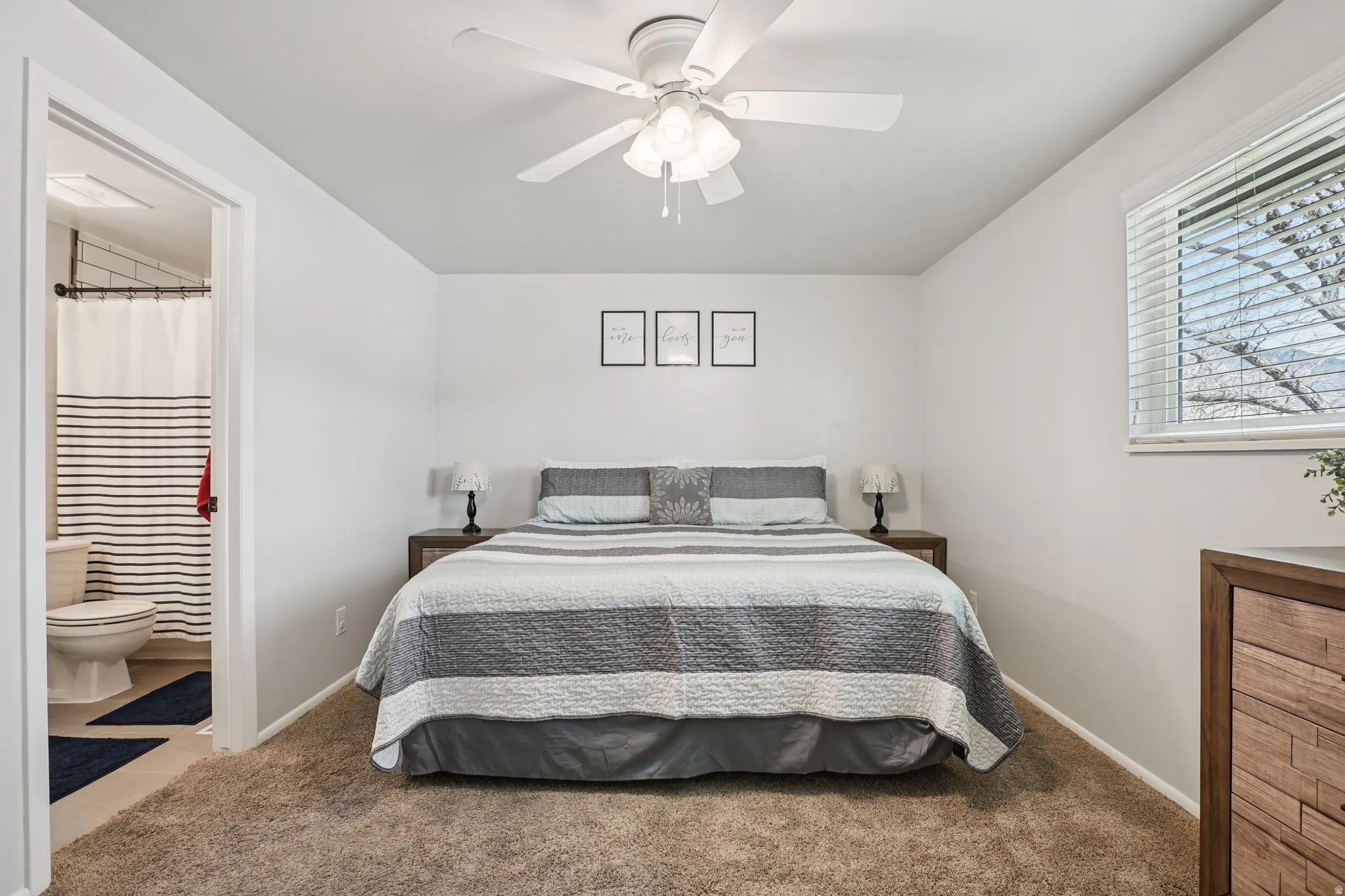 Bedroom with carpet floors, a ceiling fan, and ensuite bathroom
