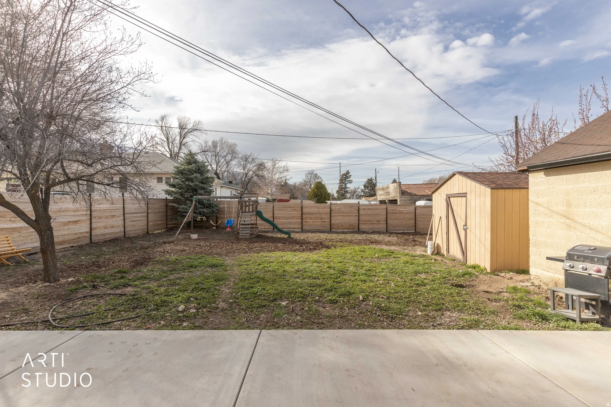 Fenced backyard with a playground and a storage unit