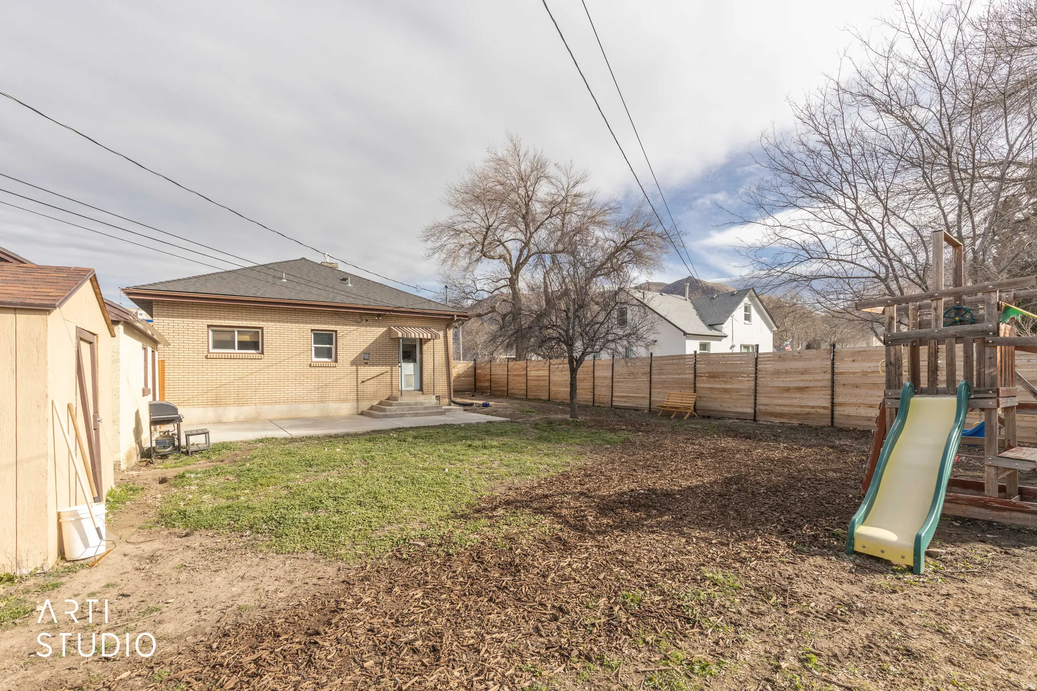 Rear view of property featuring a fenced backyard, a playground, brick siding, and a shed