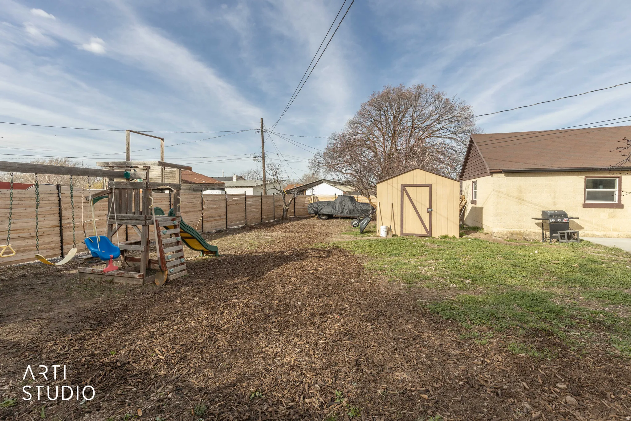 Fenced backyard with a storage shed and a playground