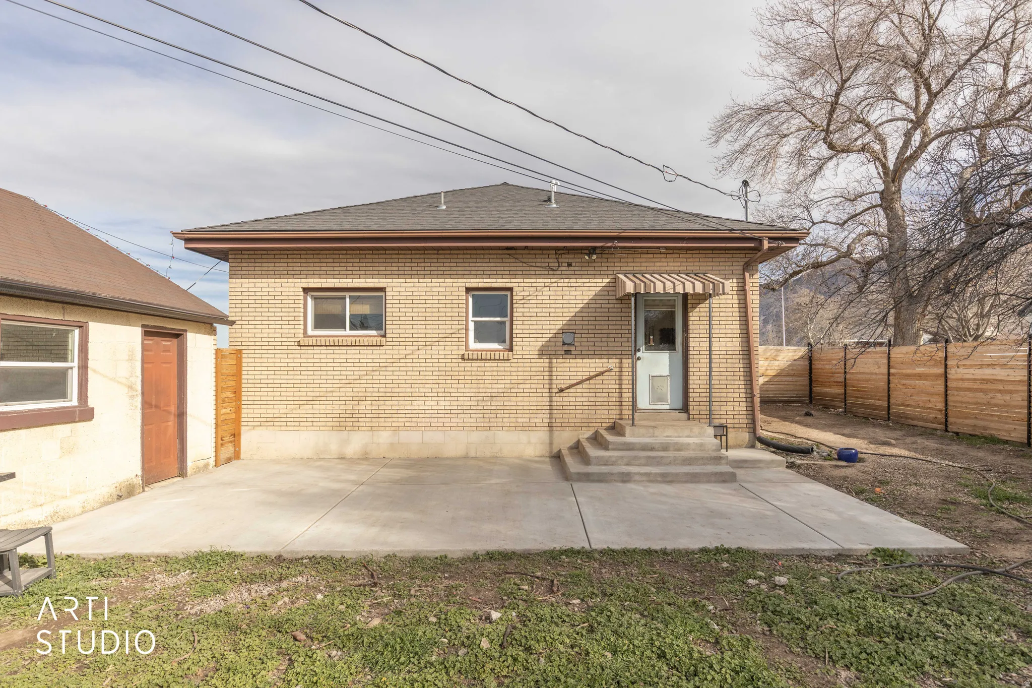 Back of house featuring brick siding, roof with shingles, entry steps, and a patio area
