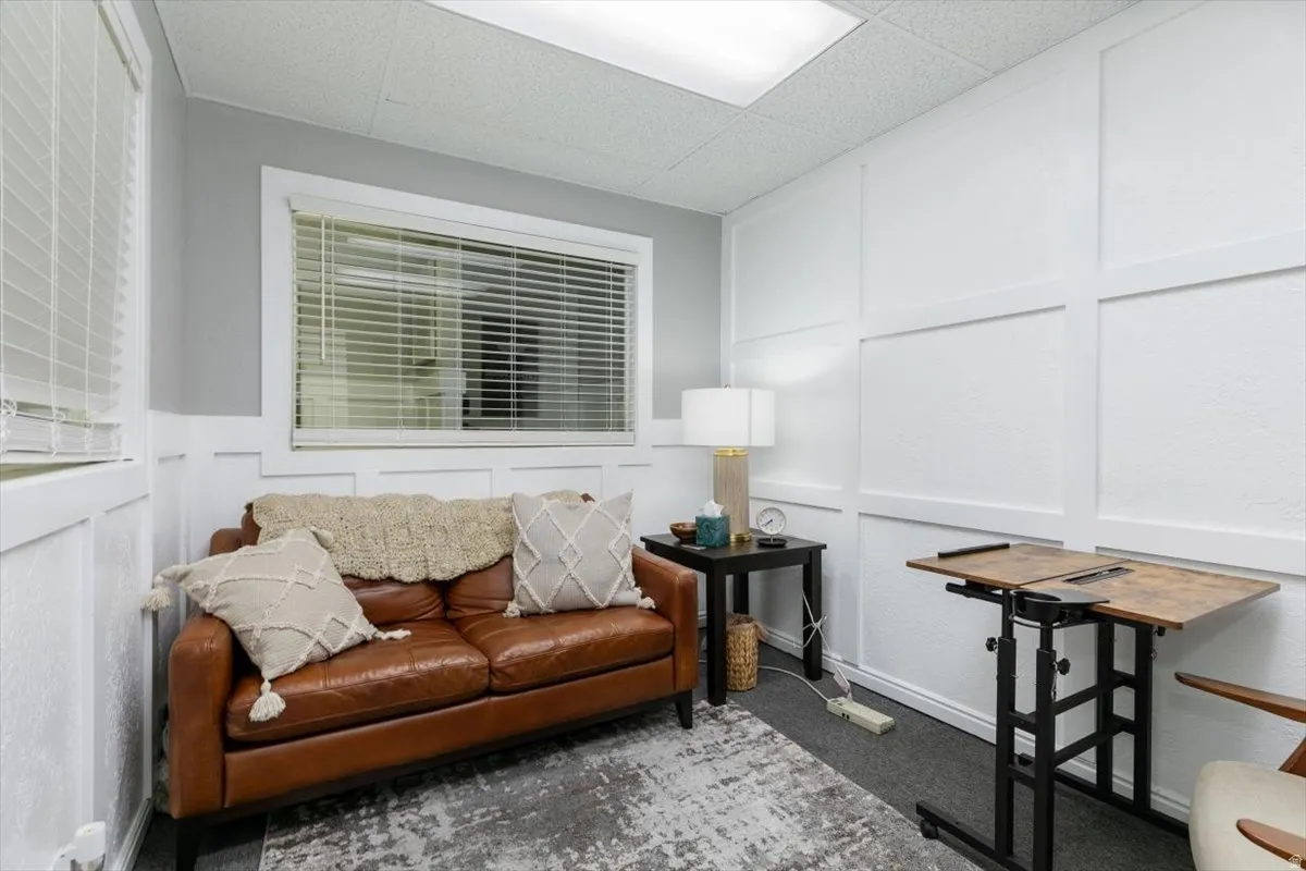 Sitting room with a decorative wall, a paneled ceiling, and carpet flooring