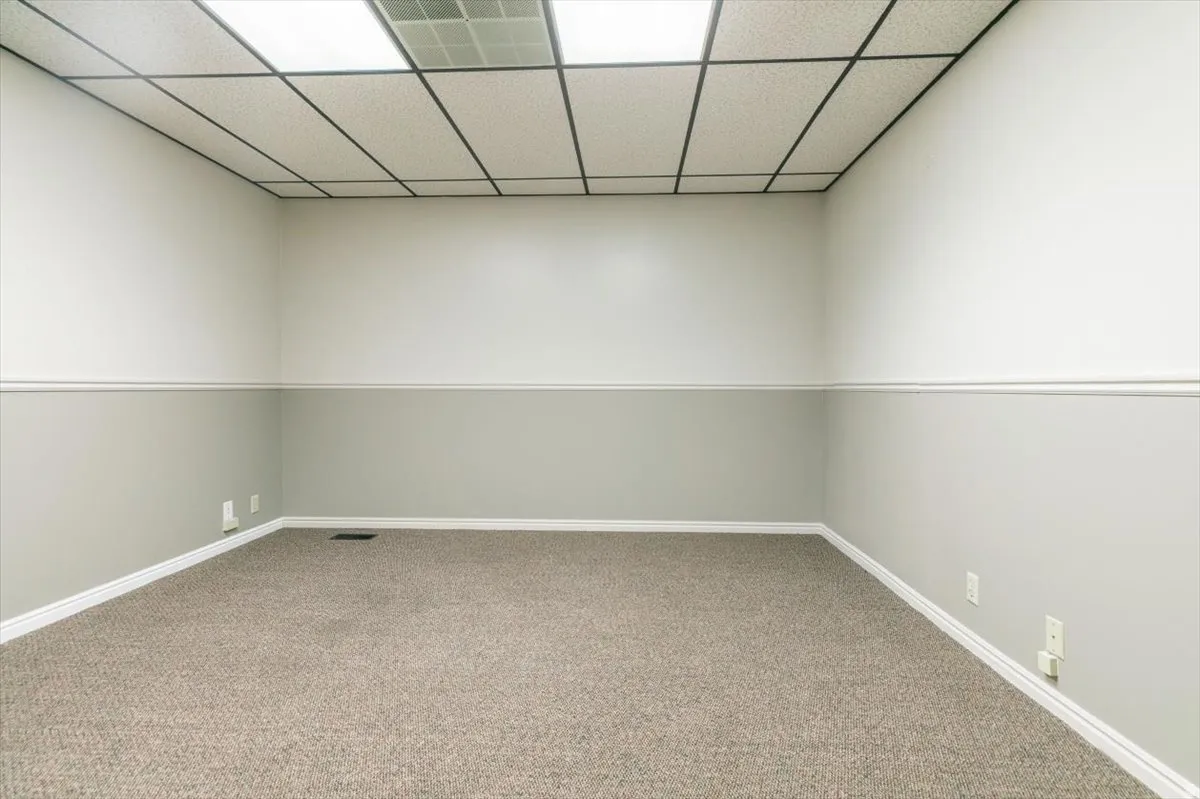Empty room featuring a paneled ceiling and carpet floors