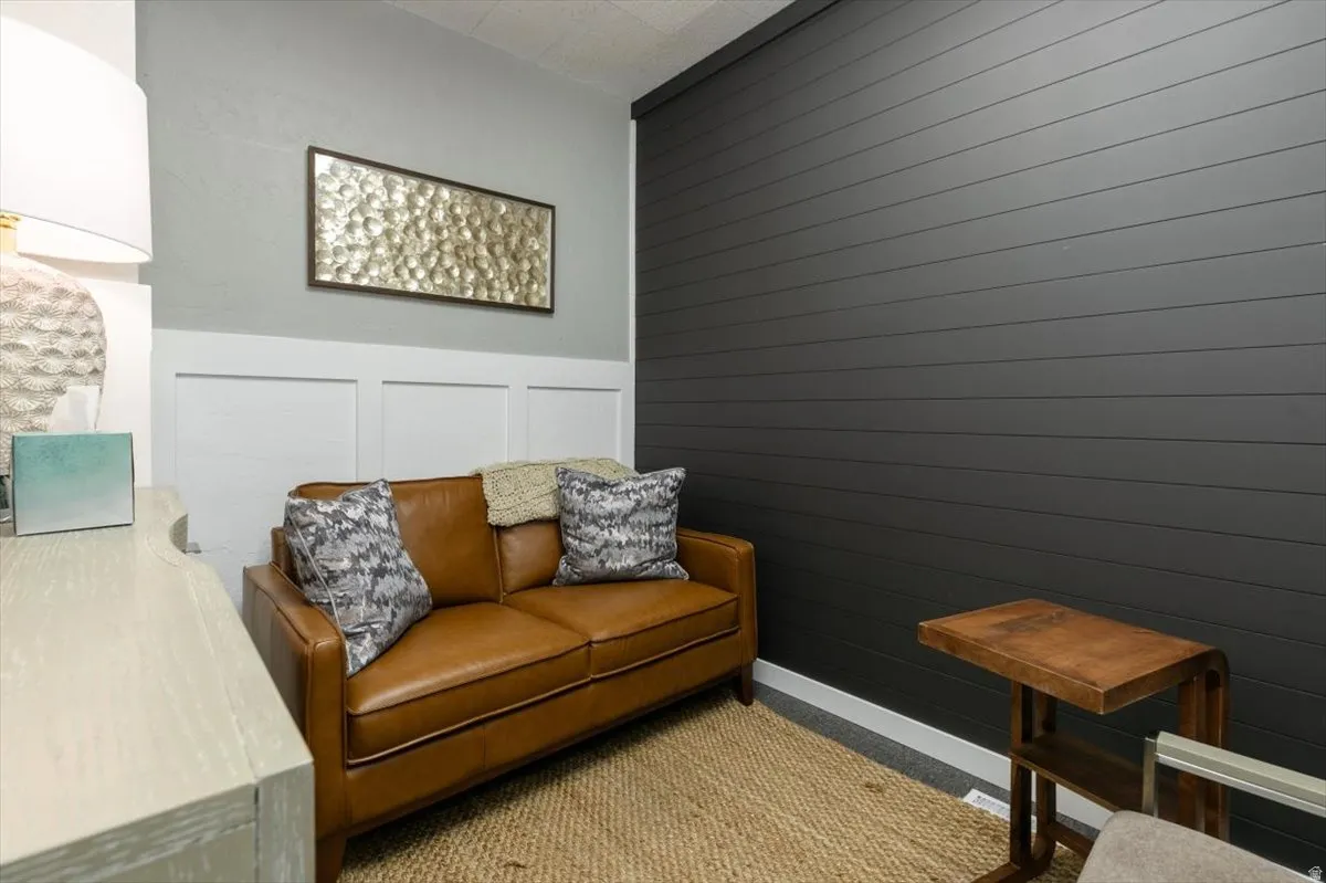 Living area featuring light colored carpet, a decorative wall, and wainscoting