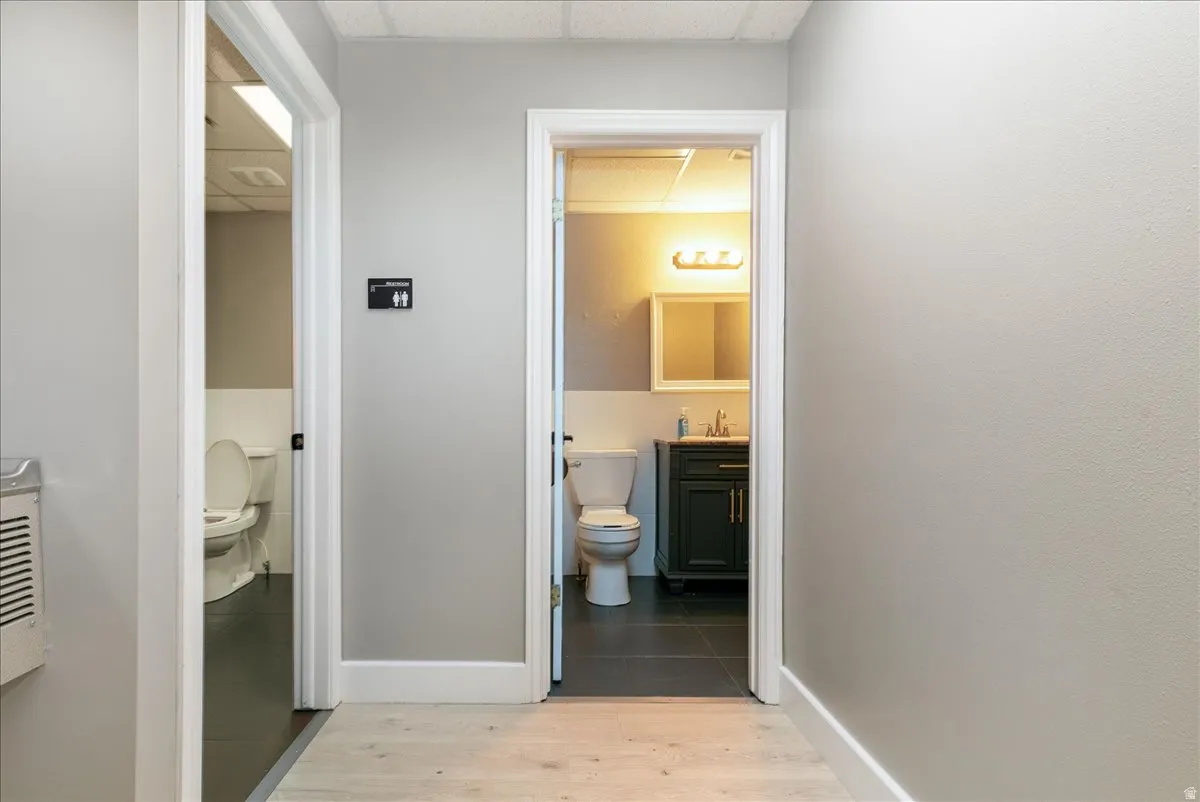 Hall featuring a drop ceiling and light wood-style floors
