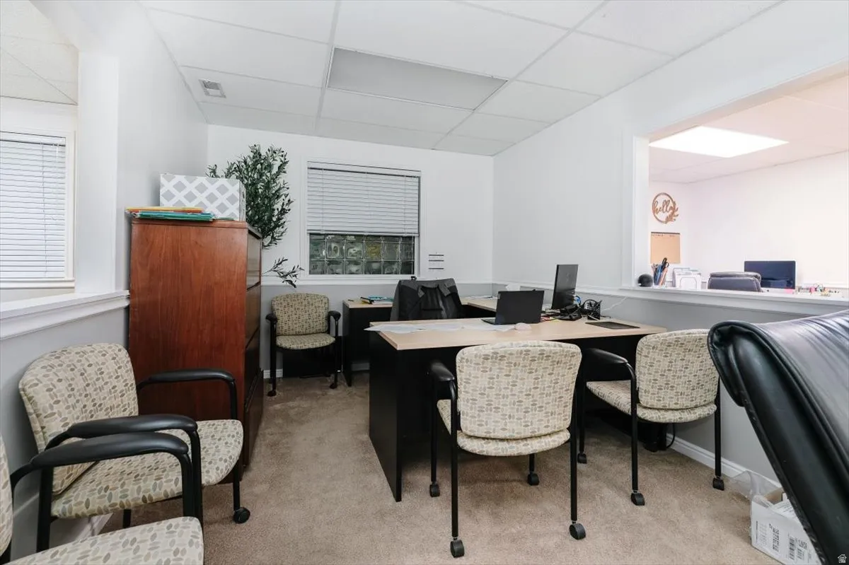 Office with a paneled ceiling and light colored carpet