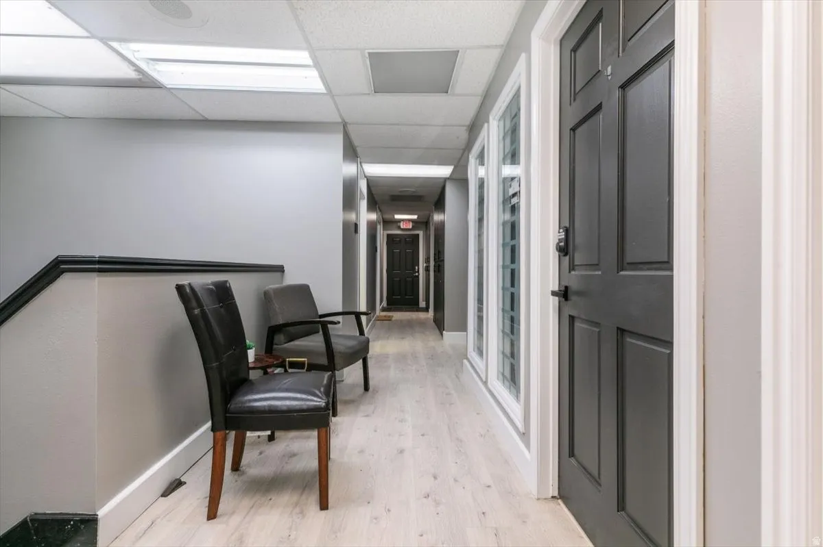 Hallway with a paneled ceiling and light wood finished floors
