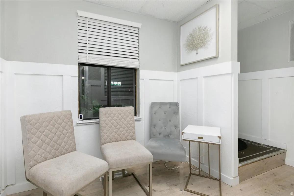Sitting room with a decorative wall, wood finished floors, and a wainscoted wall