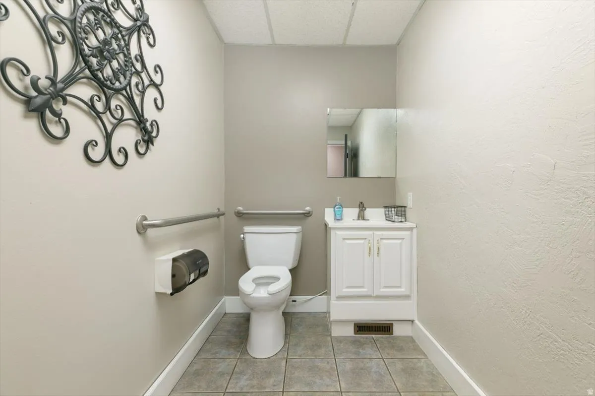 Bathroom with vanity, a drop ceiling, light tile patterned floors, and a textured wall