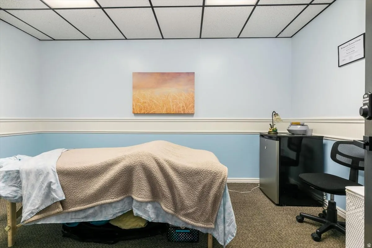 Bedroom featuring a paneled ceiling, dark colored carpet, and freestanding refrigerator