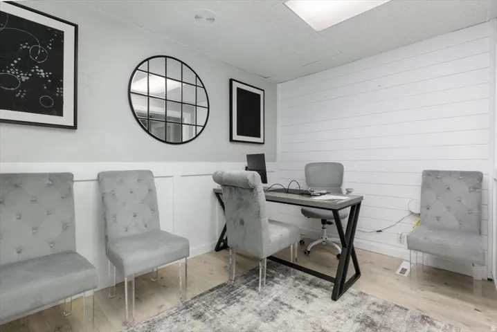 Office with wood finished floors and a wainscoted wall