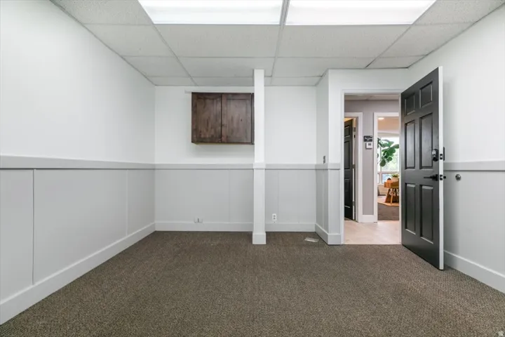 Unfurnished bedroom with a drop ceiling and dark colored carpet