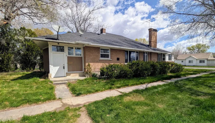 View of front of property with a chimney, a front yard, and brick siding