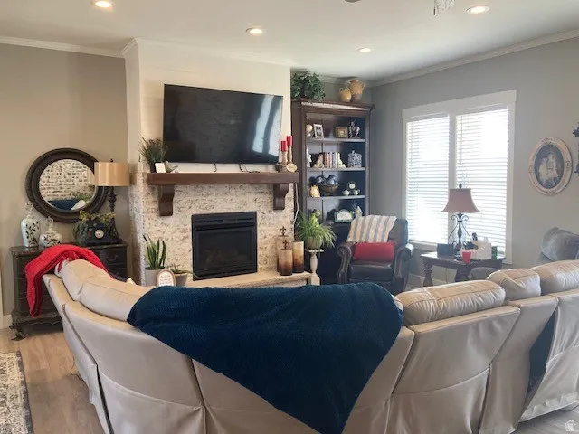 Living area with ornamental molding, a fireplace, wood finished floors, and recessed lighting