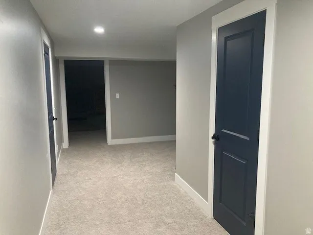 Basement Hallway featuring light carpet and baseboards