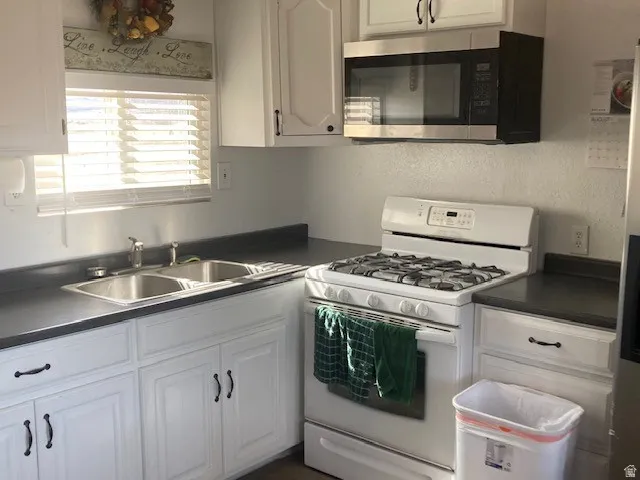 ADU Kitchen with stainless steel appliances, dark countertops, and white cabinets