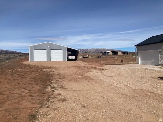 View of yard with a detached garage, an outdoor structure, a mountain view, and driveway