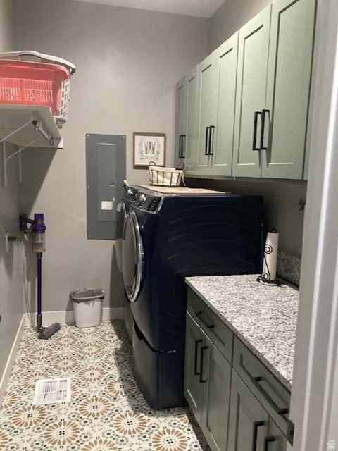 Laundry area with electric panel, cabinet space, light tile patterned floors, and separate washer and dryer